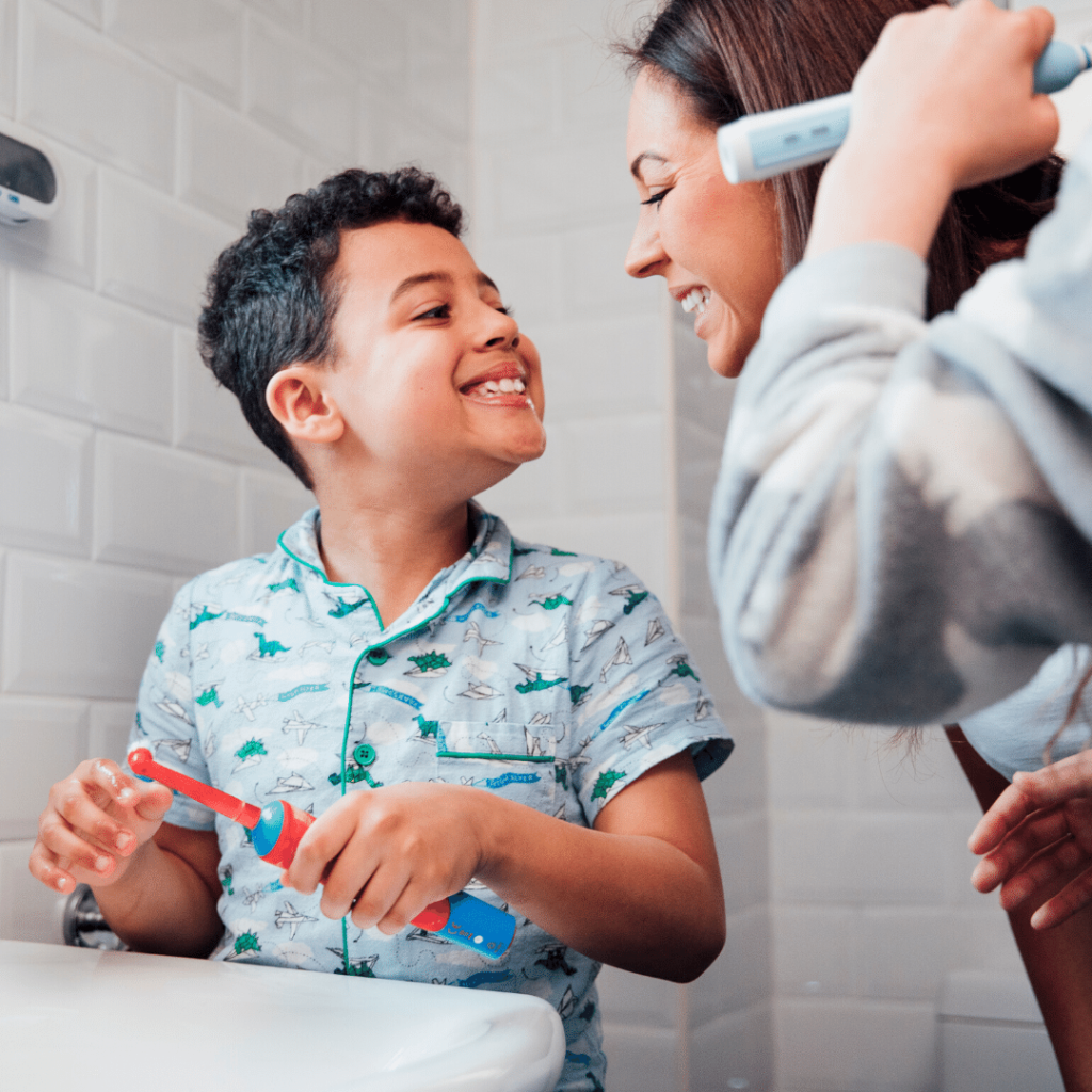 Child brushing his teeth with his mom.