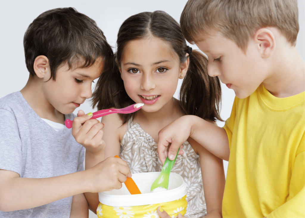 three children eating ice-cream out of one tub of icecream. 