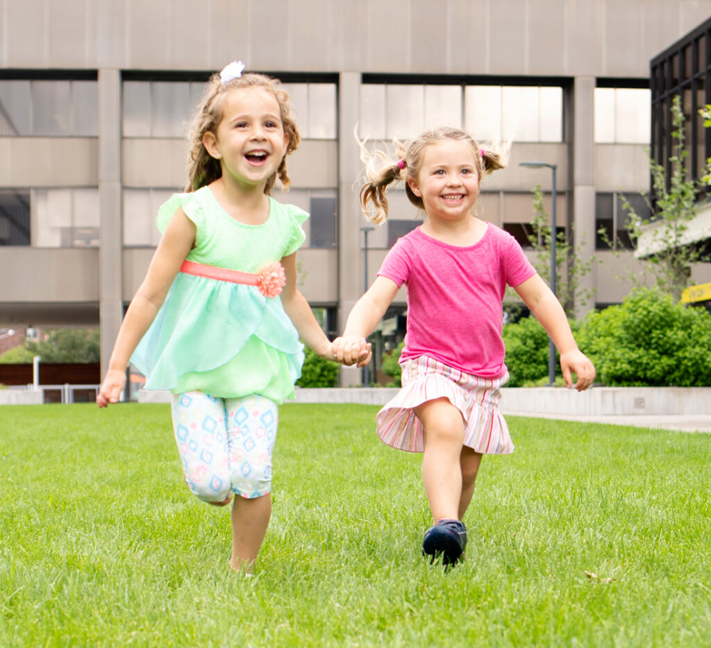 children running on the grass holding hands